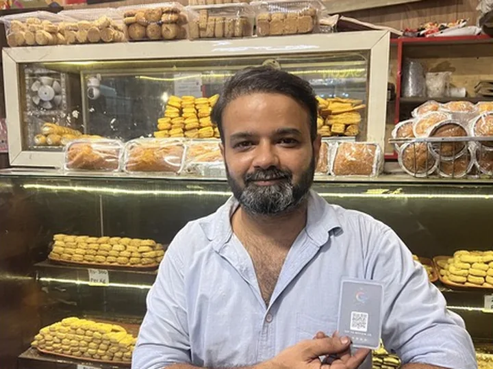 Mr. Kashif Ali of Al Juweria Bake & Bite holding his TapStar Google review card at the bakery counter
