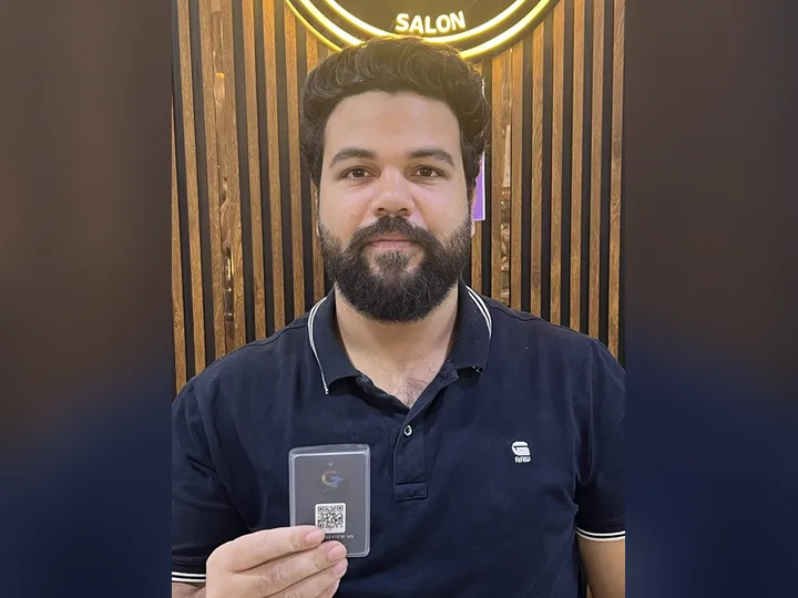 Mr. Sahil of Cuts & Curls Salon holding his TapStar Google review card