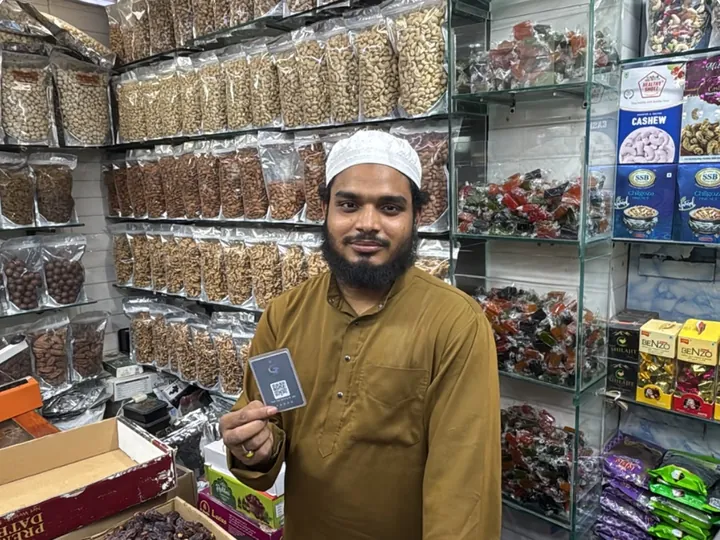 Mr. Khusdil of RK Dates holding his TapStar business card in his dry fruits shop